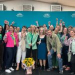 Sian Berry and Brighton and Hove Green Party members celebrating on stage after the election count. All smiling at the camera.